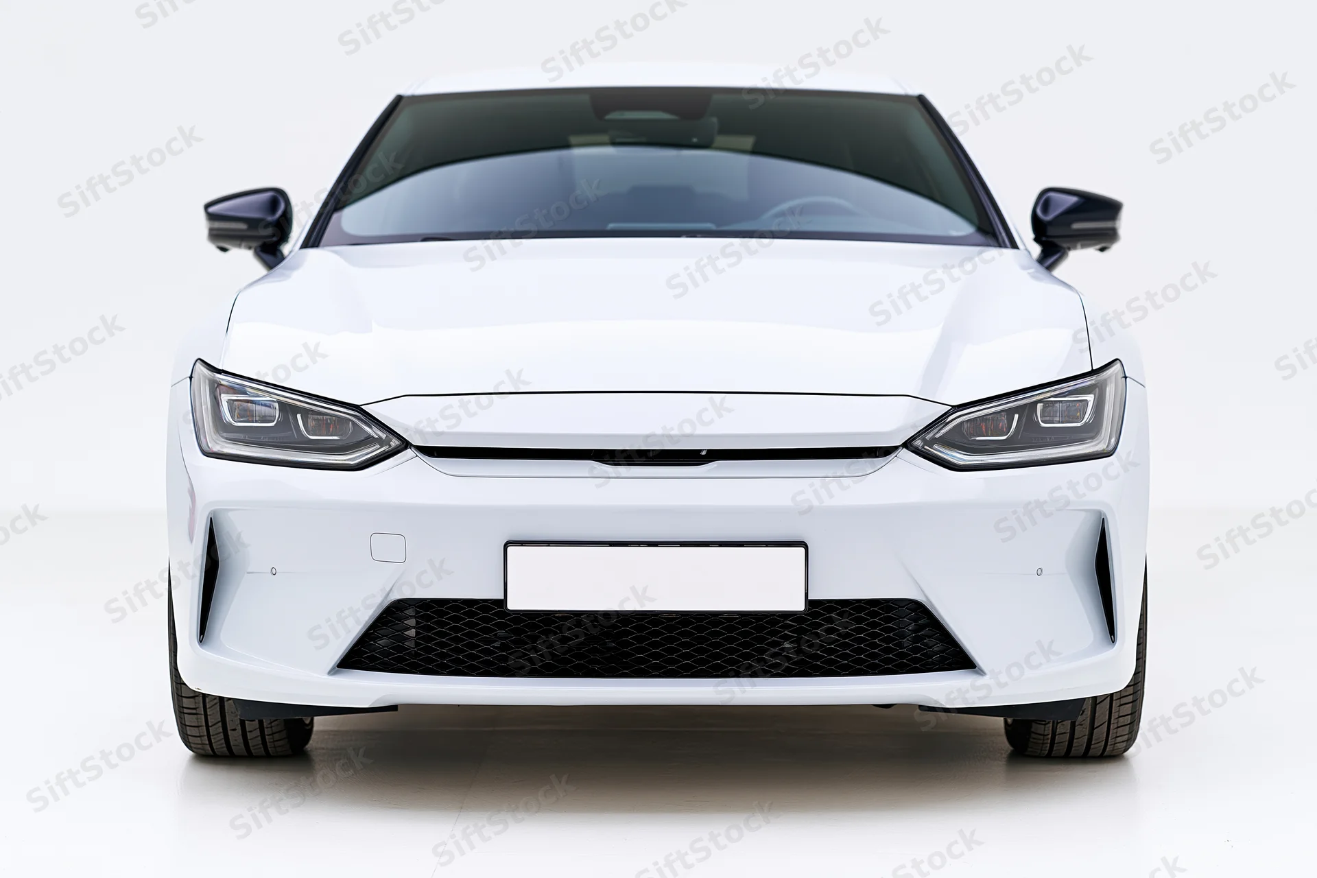 White modern electric sedan viewed straight-on from front in studio setting