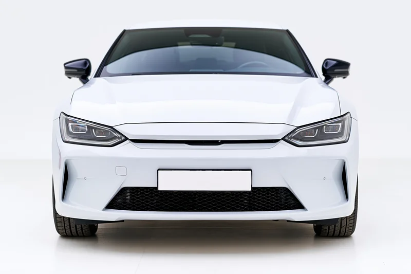 White modern electric sedan viewed straight-on from front in studio setting