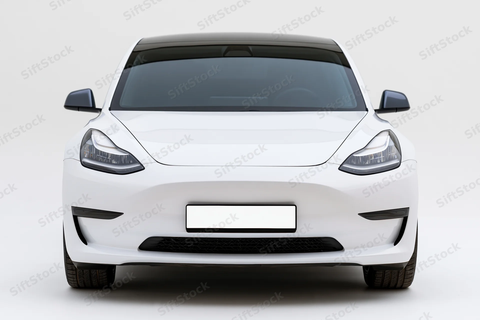 White modern electric sedan viewed straight-on from front in studio setting