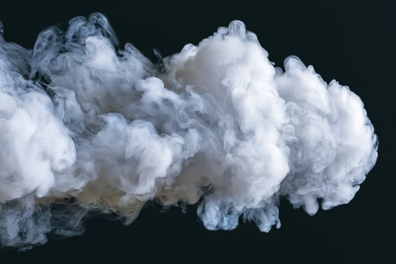 White smoke cloud drifting and dispersing midair against black background