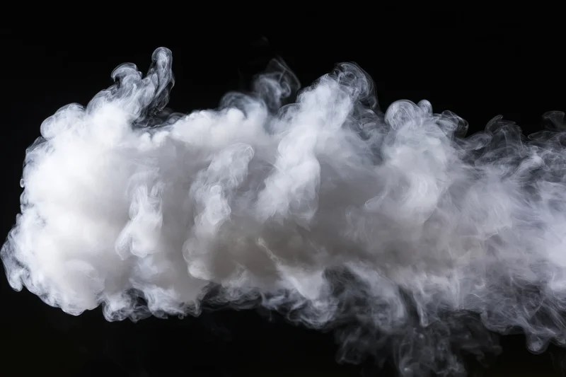 White smoke cloud drifting and dispersing mid-air against black background