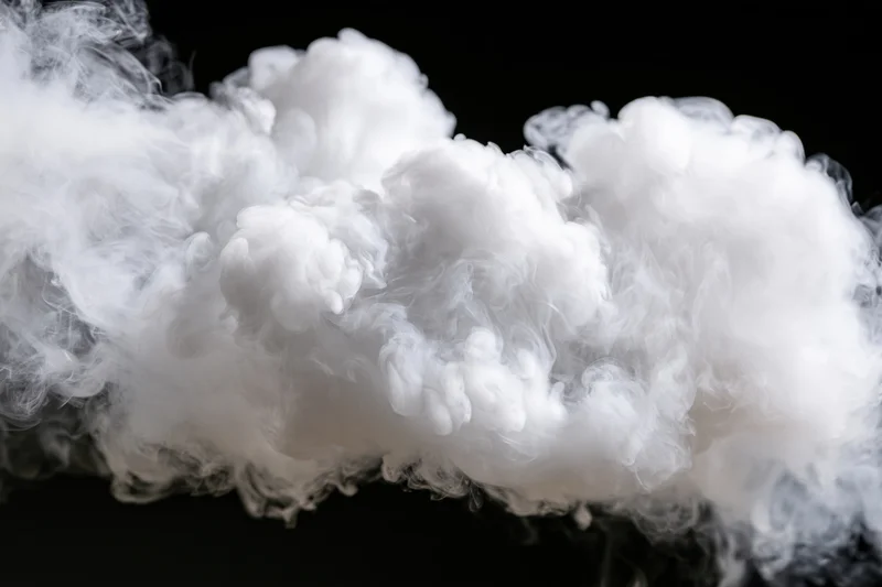 White smoke cloud drifting and dispersing mid-air against black background