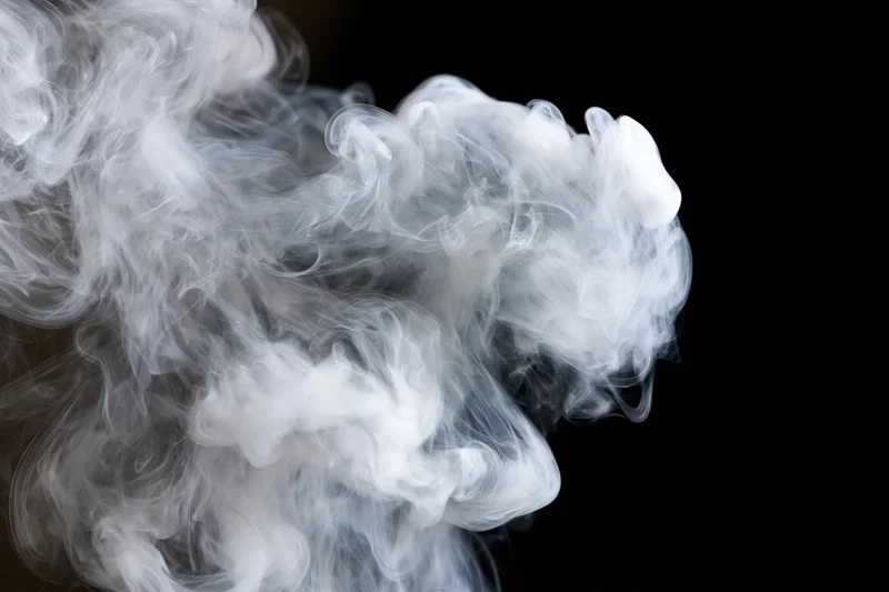White smoke curling and billowing upward against a black background