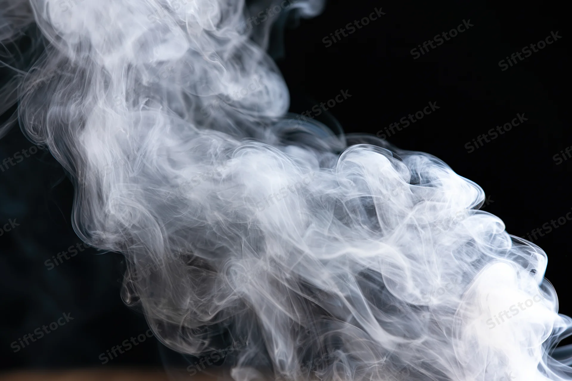 White smoke curling and billowing upward against a black background