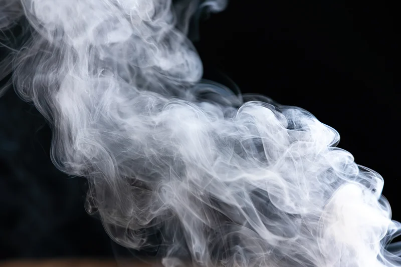 White smoke curling and billowing upward against a black background