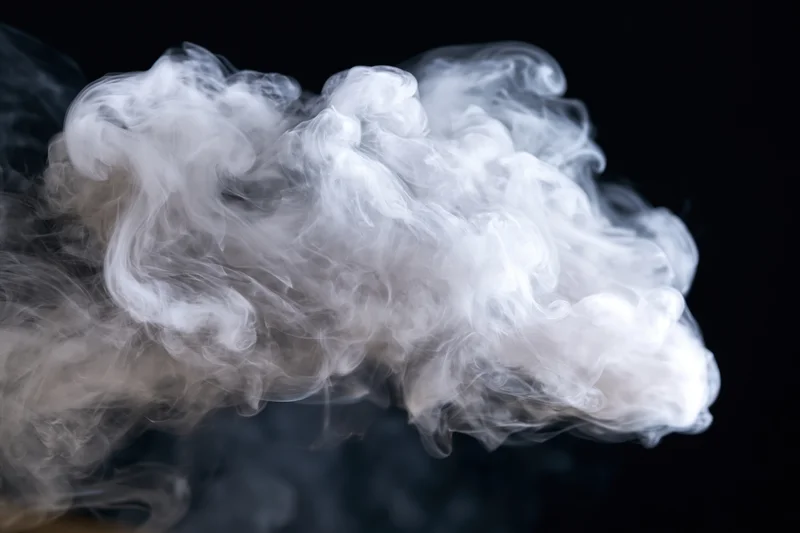 White smoke curling and billowing upward against a black background