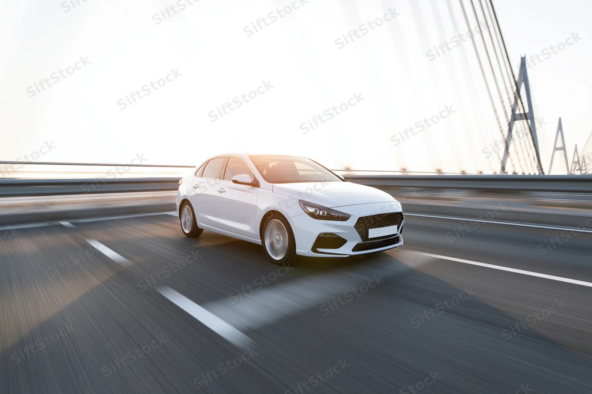 White sport sedan driving at speed across cable-stayed bridge