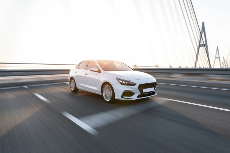 White sport sedan driving at speed across cable-stayed bridge
