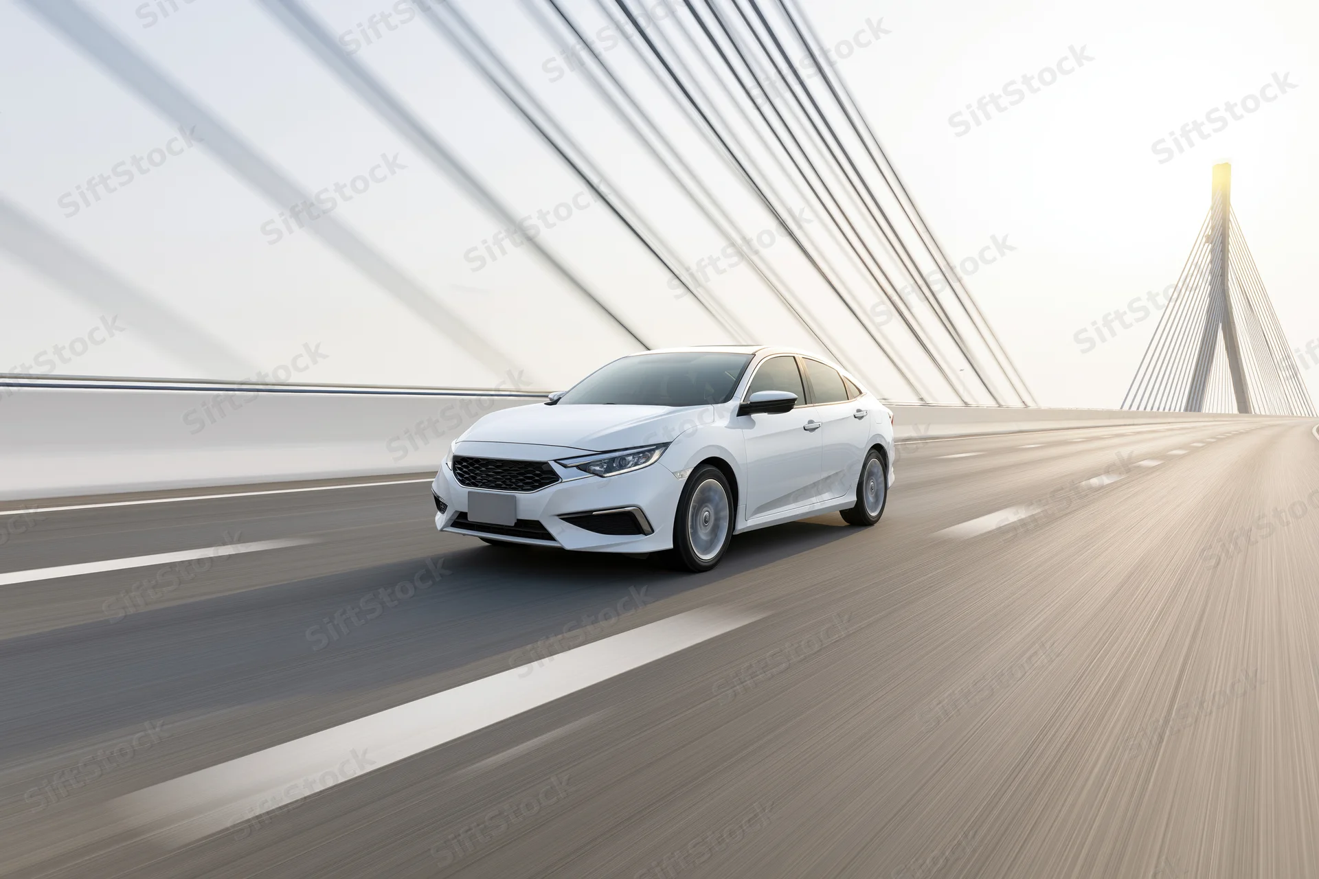 White sedan driving at speed across a cable-stayed bridge