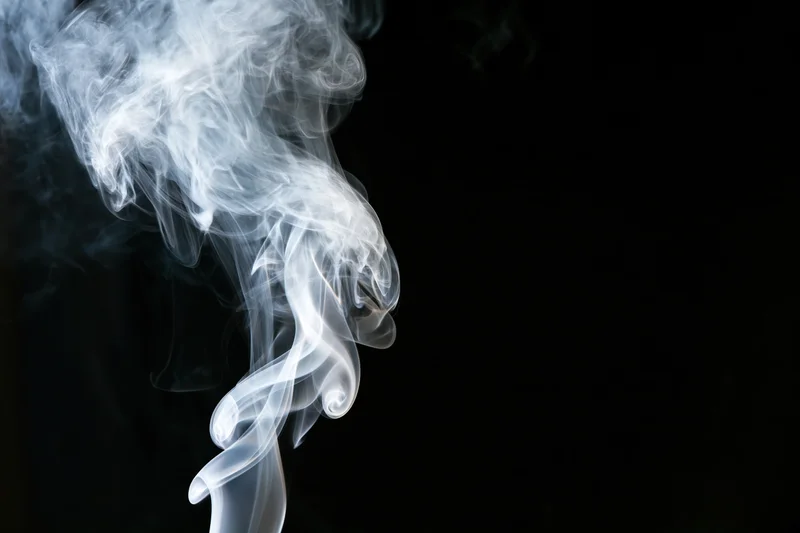 White smoke curling upward against a black background