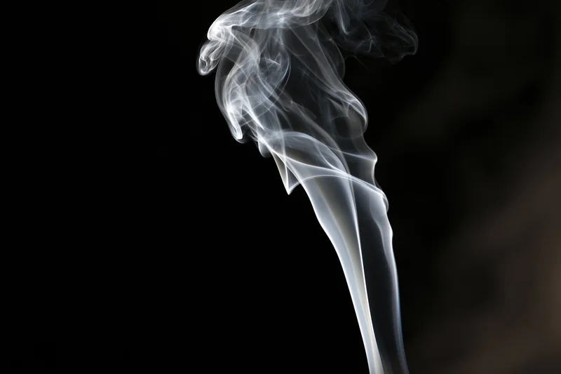 Wispy white smoke curling upward against a black background