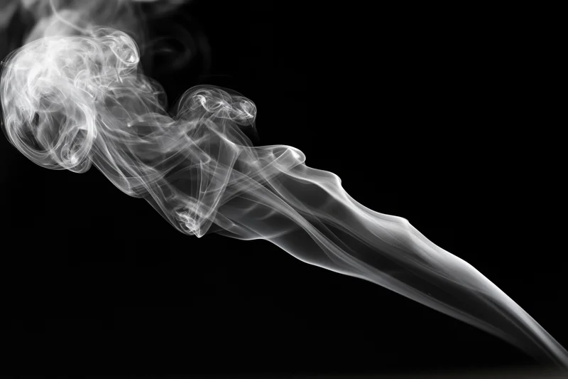Wispy white smoke curling and dissipating upward against a pure black background