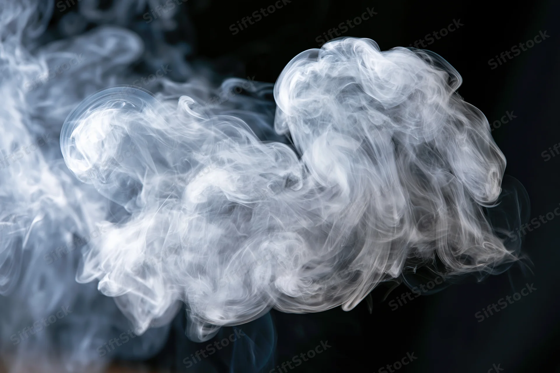 White smoke swirling in layered tendrils against dark background