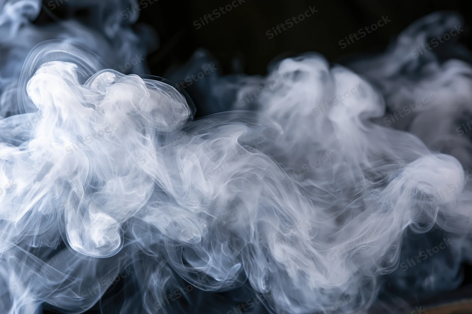 White smoke swirling in layered tendrils against a dark background