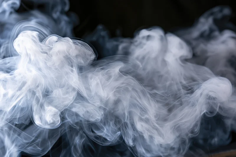 White smoke swirling in layered tendrils against a dark background