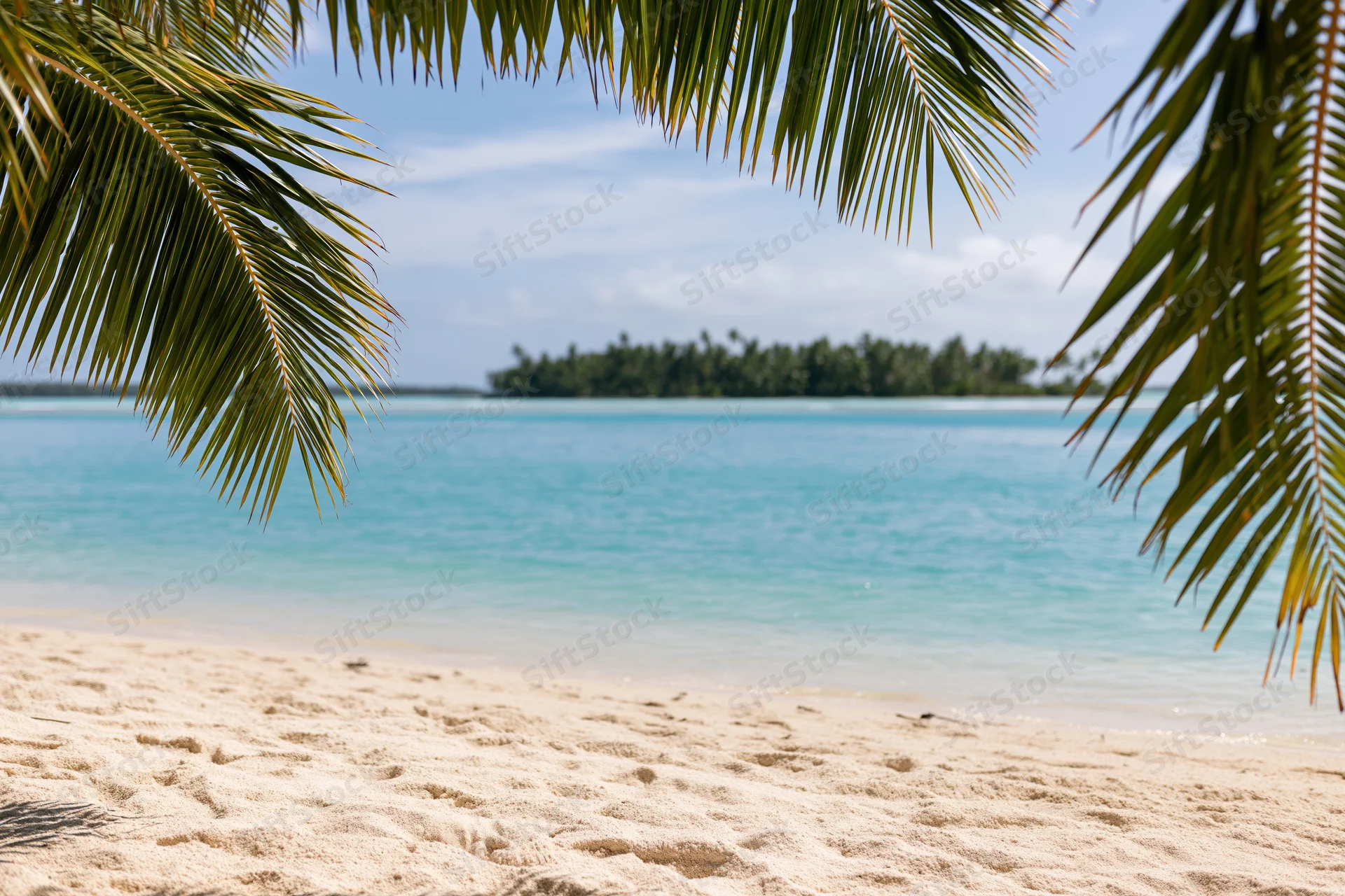 Tropical beach framed by palm fronds overlooking turquoise ocean and distant island