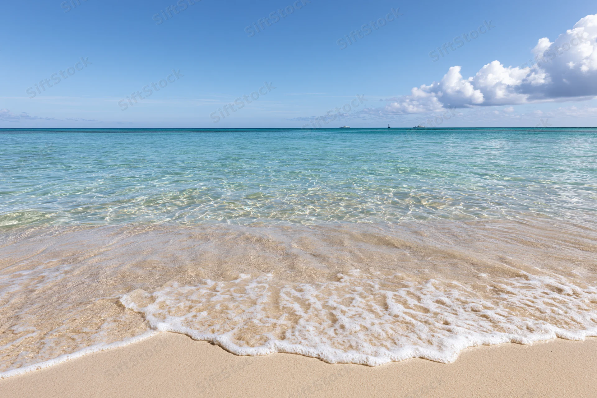 Gentle waves rolling onto a sandy beach under a clear blue sky