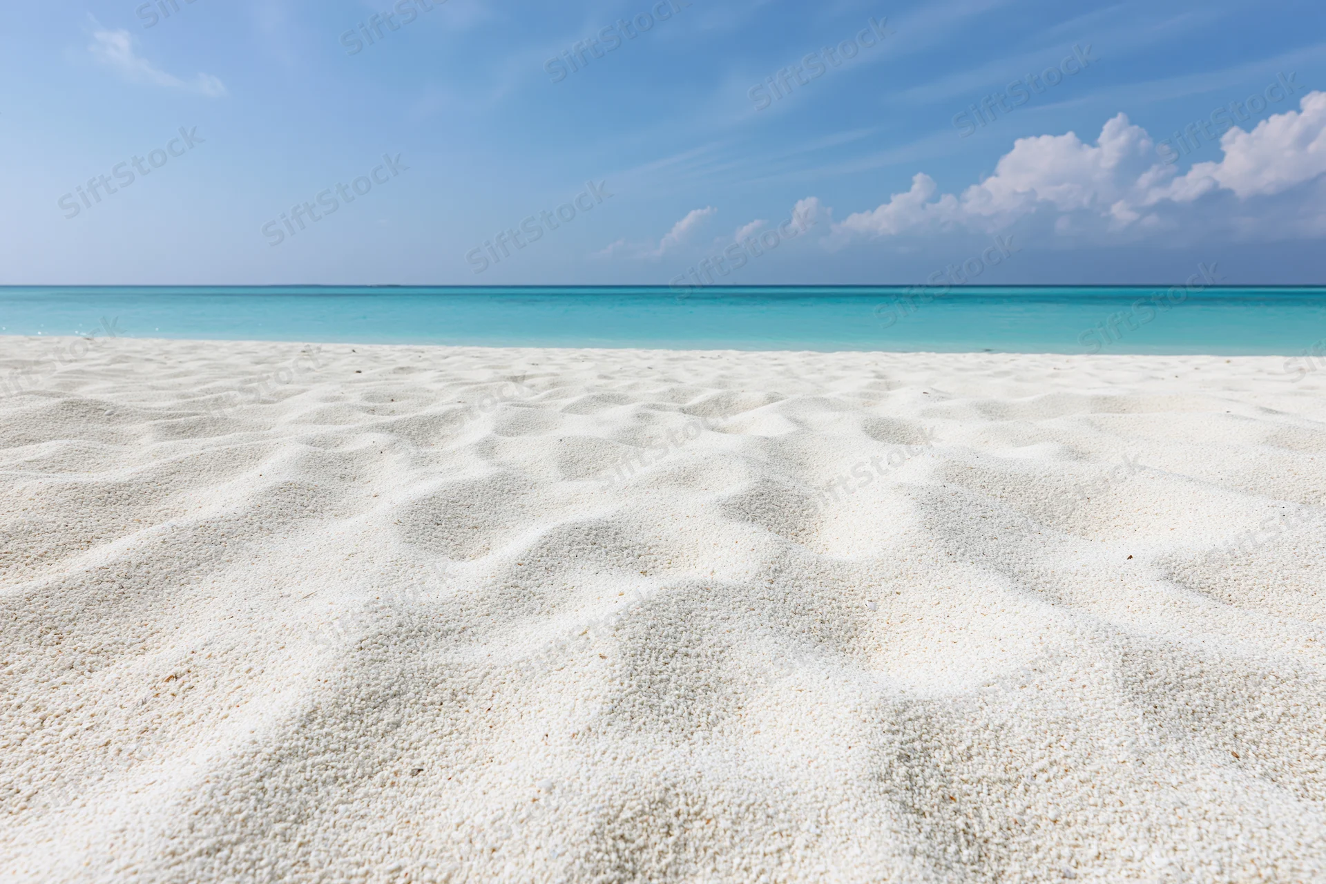 White sandy beach meeting turquoise ocean under clear blue sky