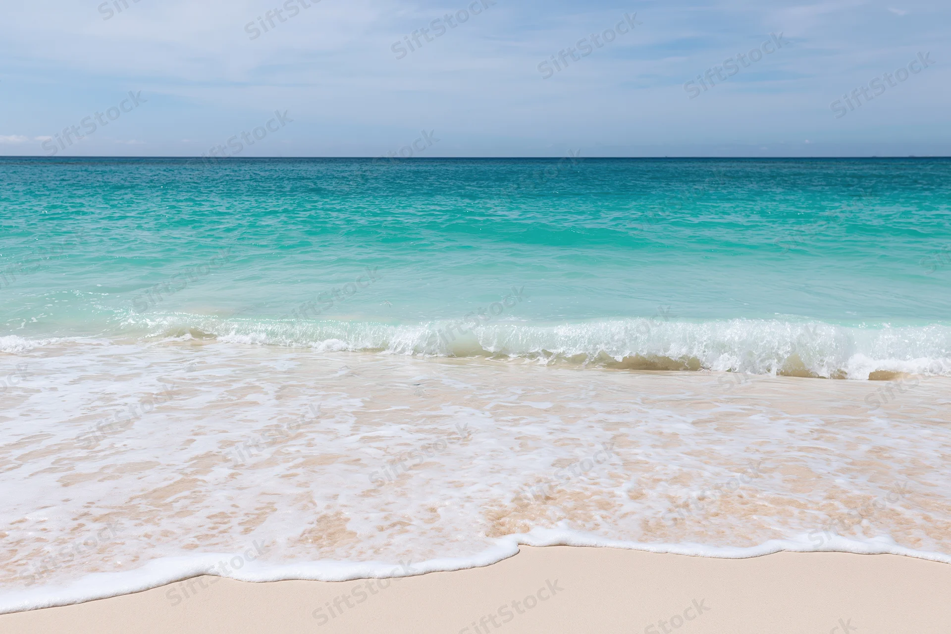 Gentle waves rolling onto a sandy beach under a clear blue sky