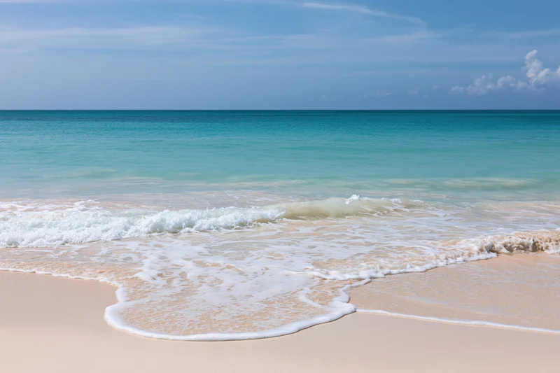 Gentle waves rolling onto a sandy beach under a clear blue sky