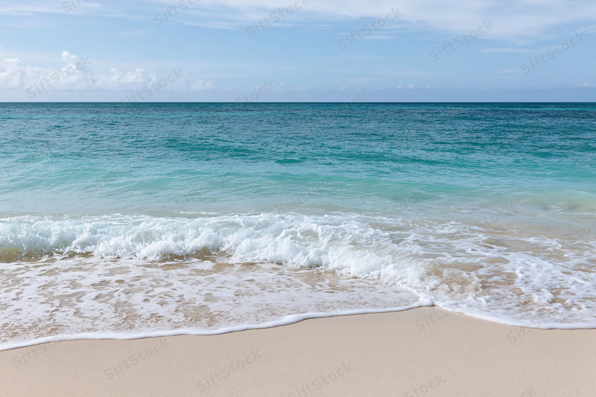 Gentle waves rolling onto a sandy beach under a clear blue sky