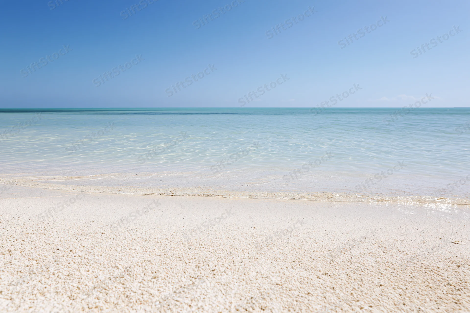 White sandy beach meeting calm turquoise ocean under clear blue sky