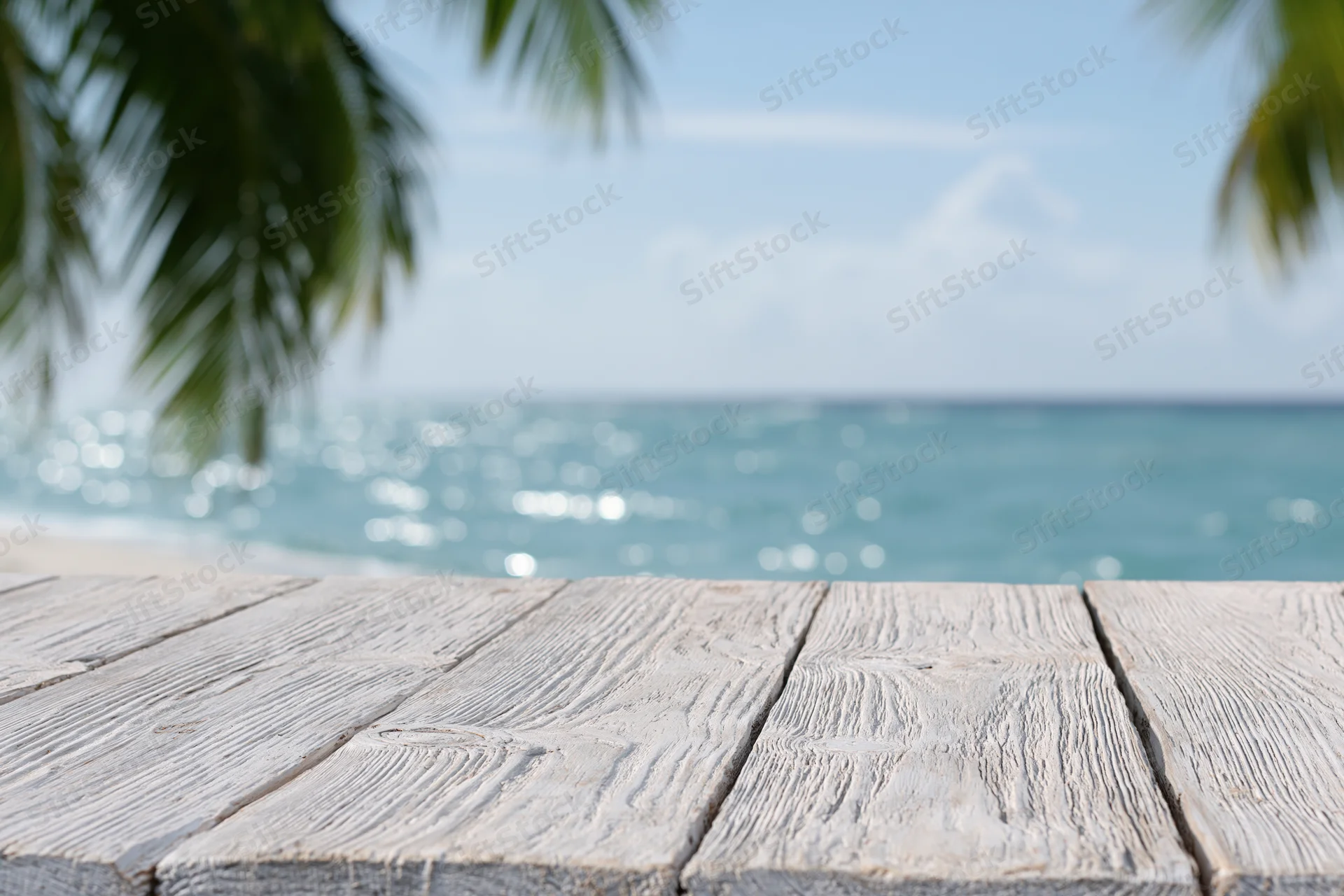 Wooden table on a tropical beach with ocean and palm trees in the background