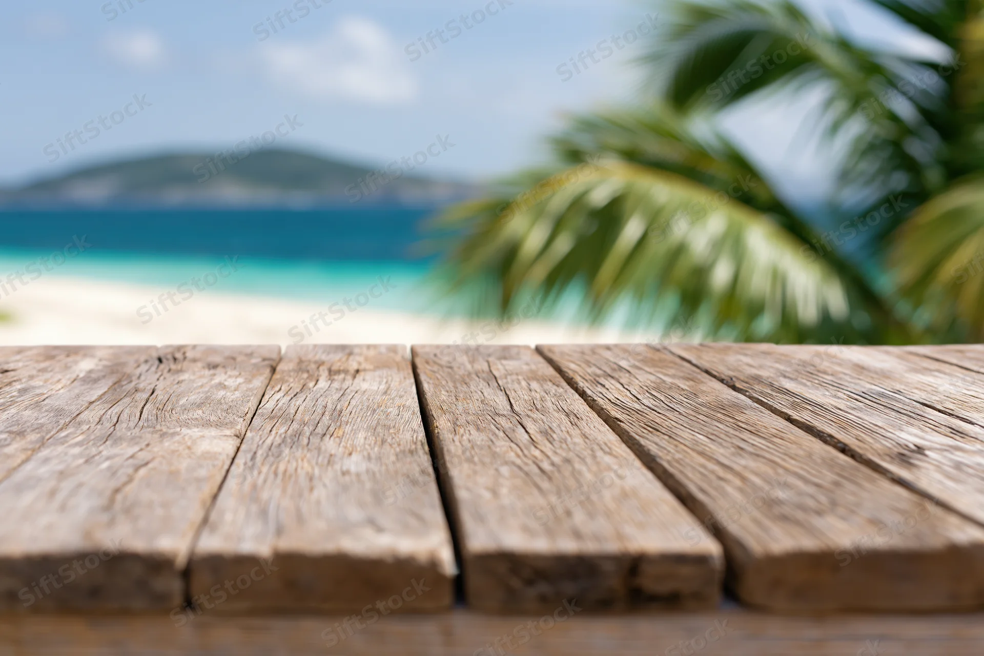 Weathered wooden table in front of a tropical beach with palm trees and ocean view