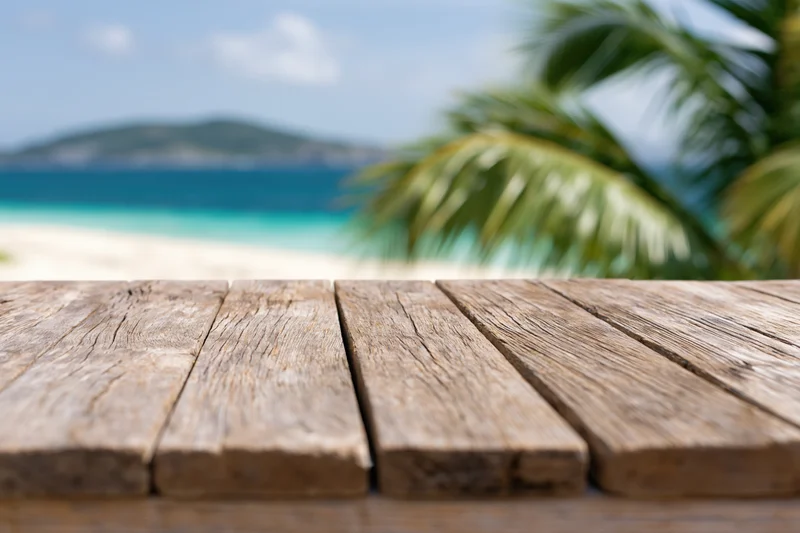 Weathered wooden table in front of a tropical beach with palm trees and ocean view