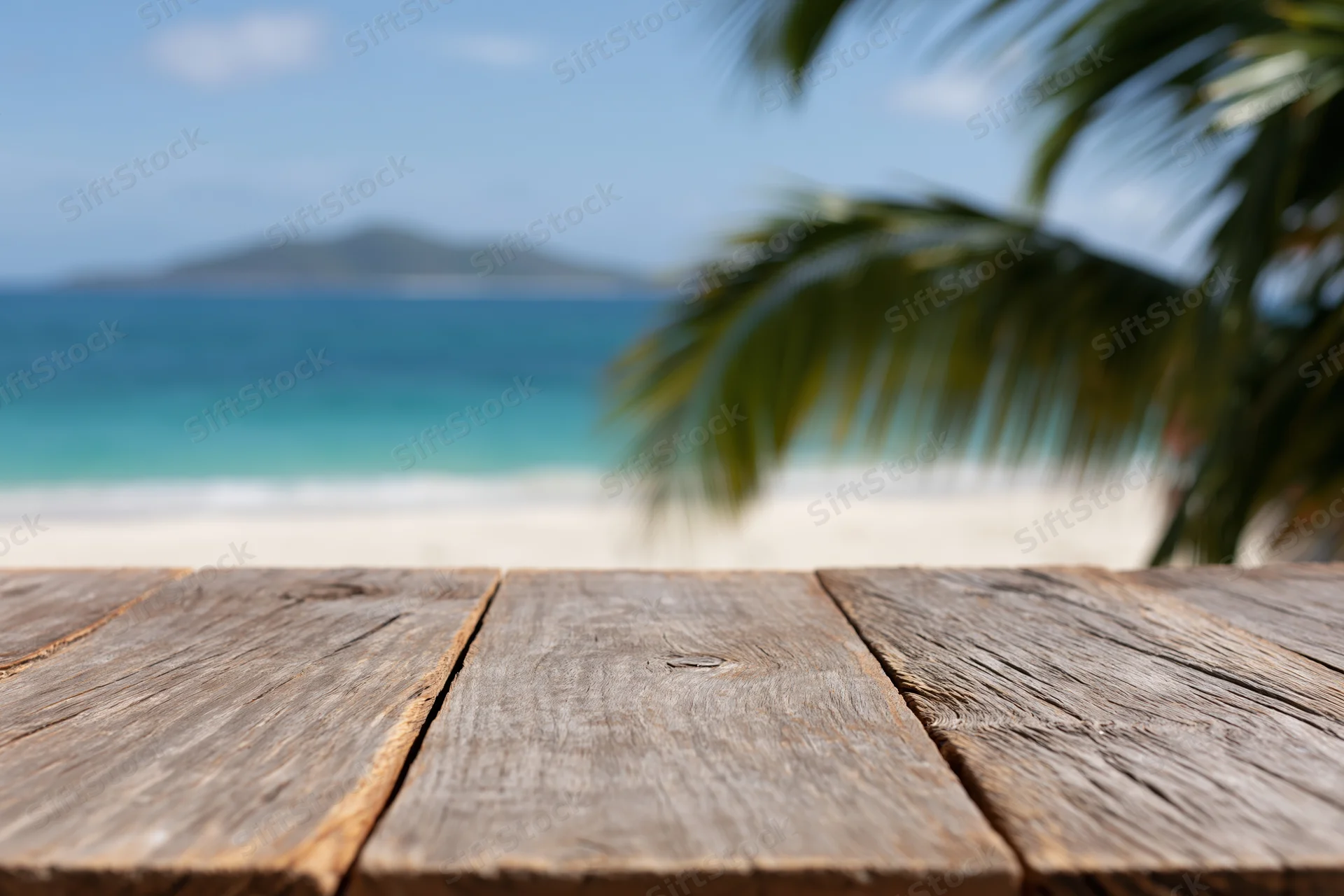Wooden table overlooking a tropical beach with palm fronds and ocean in the distance