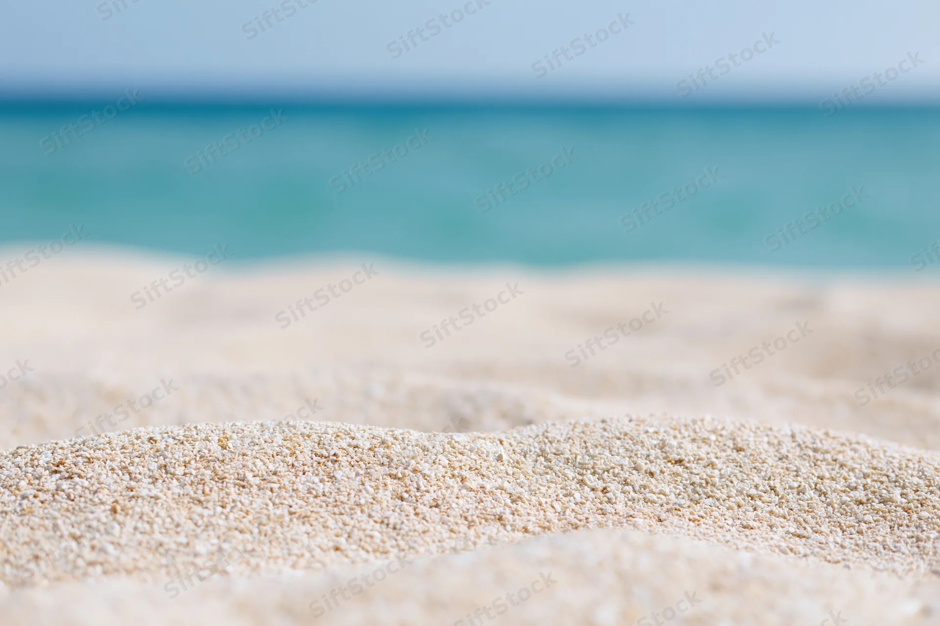 Closeup of fine sand grains on a beach with ocean in the background