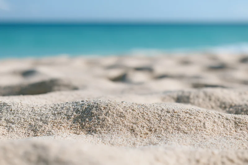 Close-up of textured sand on a beach with ocean in the background