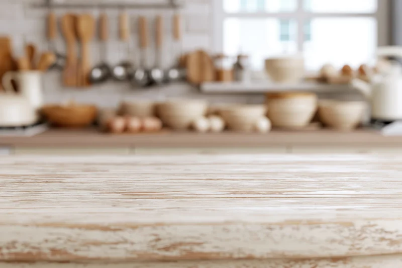 Wooden kitchen countertop with blurred cooking utensils and ingredients in background