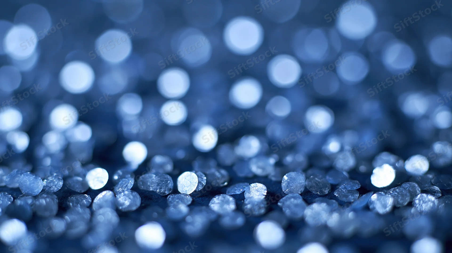 Closeup of blue glitter particles with bokeh effect on dark surface