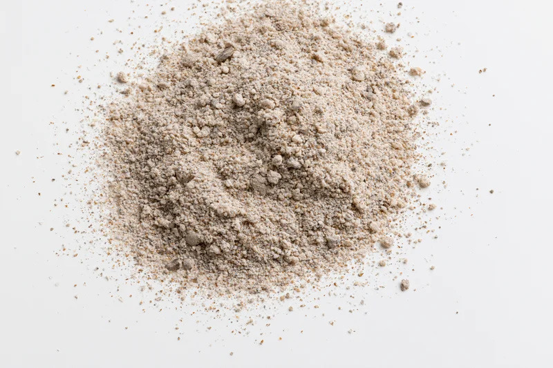 Pile of beige granular powder on white surface