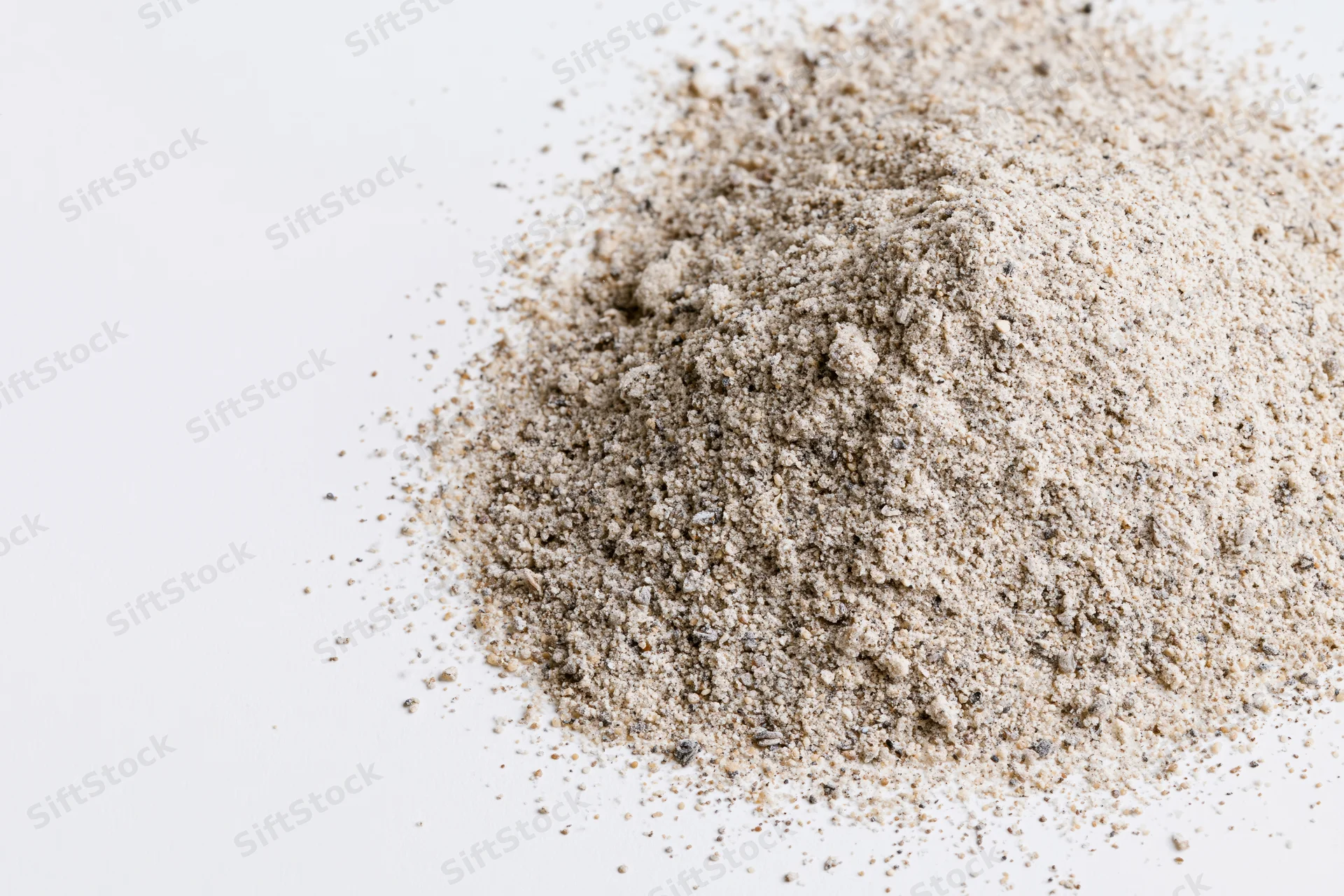 Pile of beige granular powder on white surface with copyspace