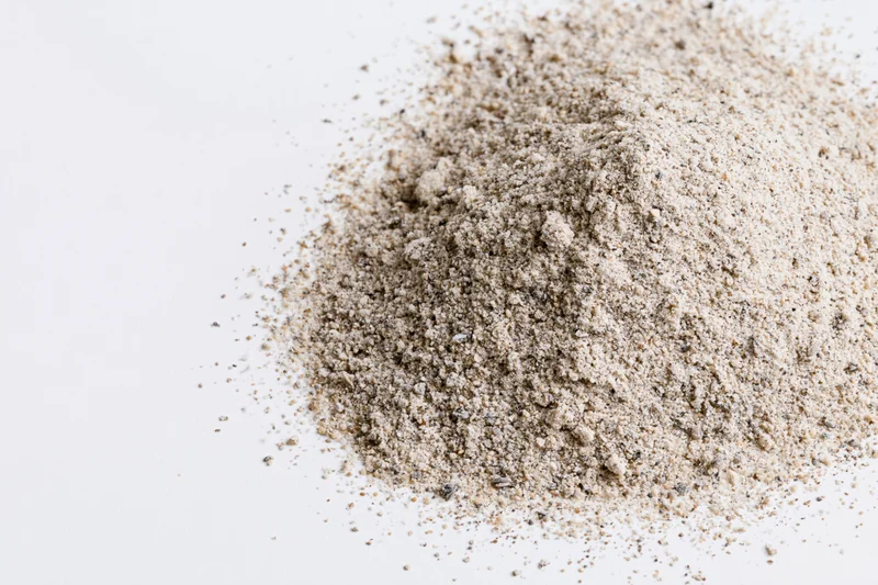 Pile of beige granular powder on white surface with copyspace