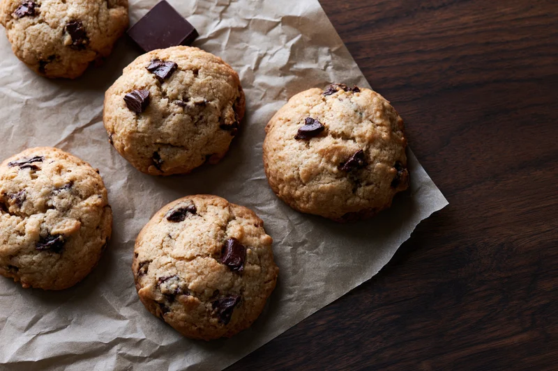 Chocolate chip cookies on crumpled parchment paper on dark wooden table