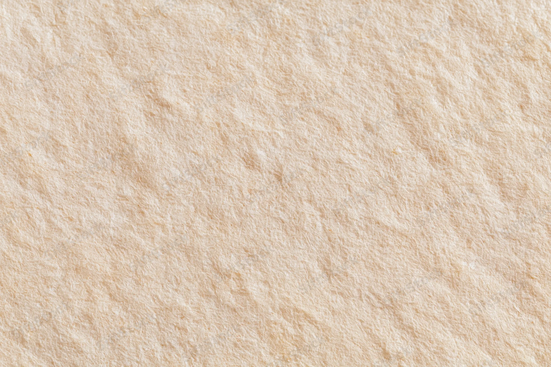 Closeup of beige textured paper surface with subtle fibrous grain and matte finish