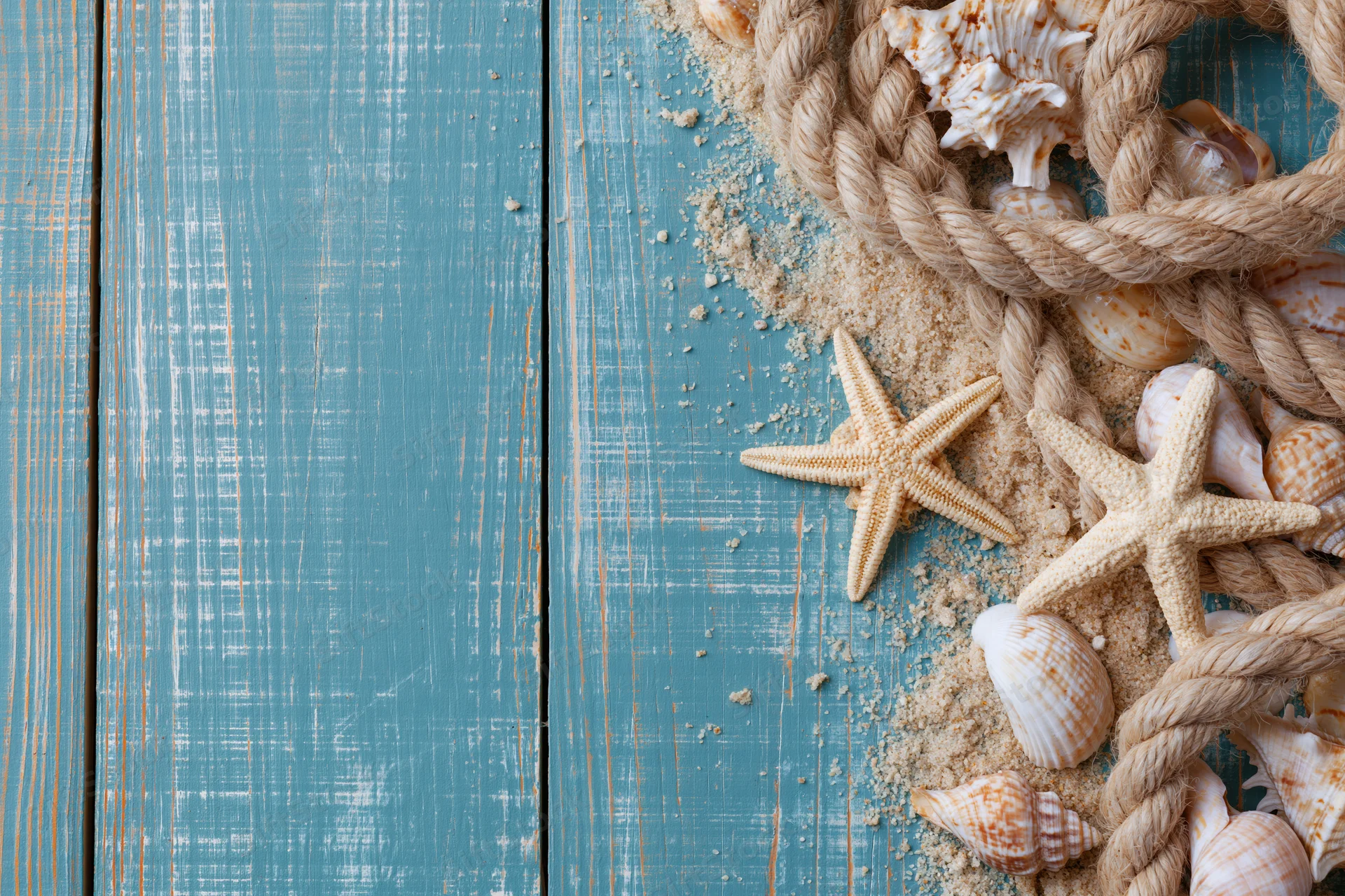 Starfish and seashells with rope and sand on blue weathered wooden planks