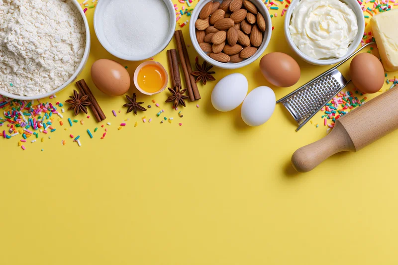 Baking ingredients arranged on yellow surface with copyspace below