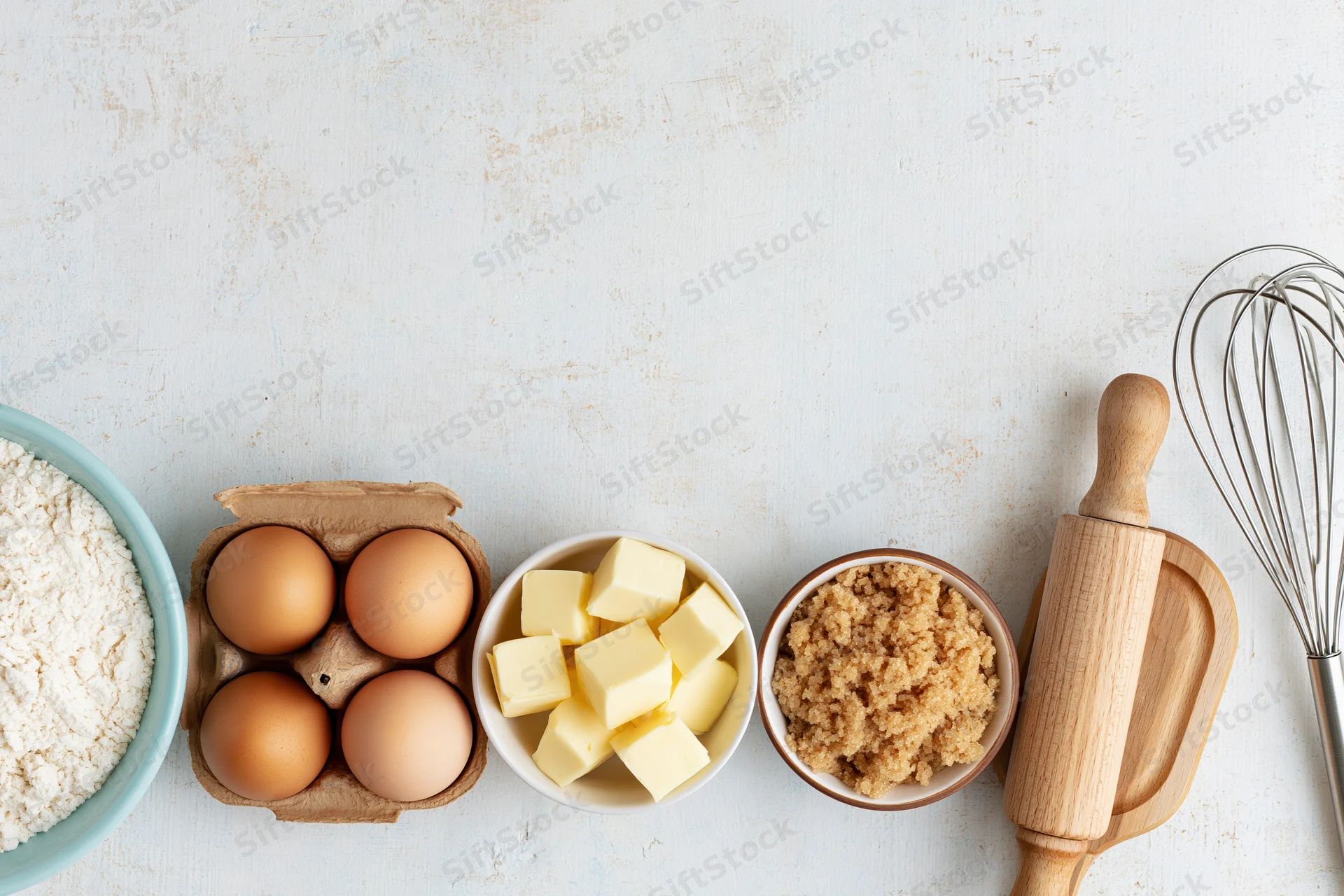 Baking ingredients arranged on a white countertop with utensils