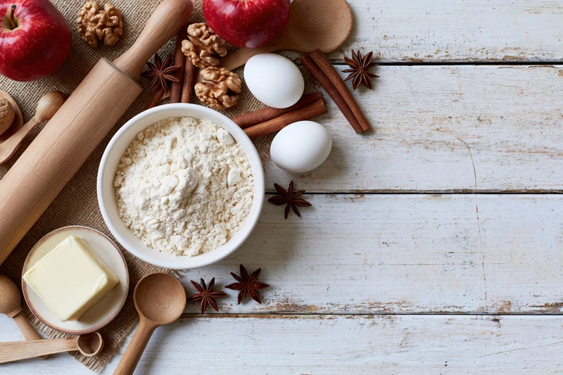 Baking ingredients arranged on a white wooden countertop with copyspace