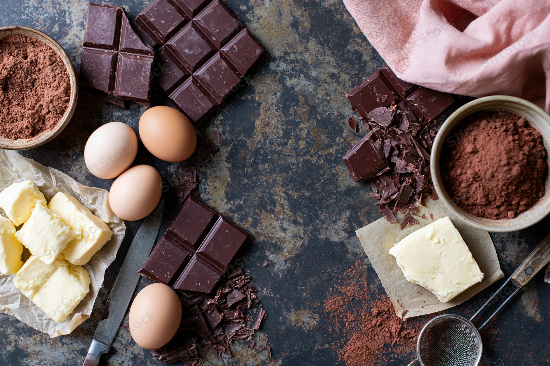 Chocolate and baking ingredients arranged on a dark rustic countertop with copyspace