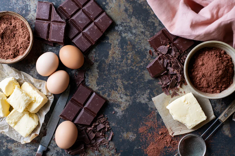 Chocolate and baking ingredients arranged on a dark rustic countertop with copyspace