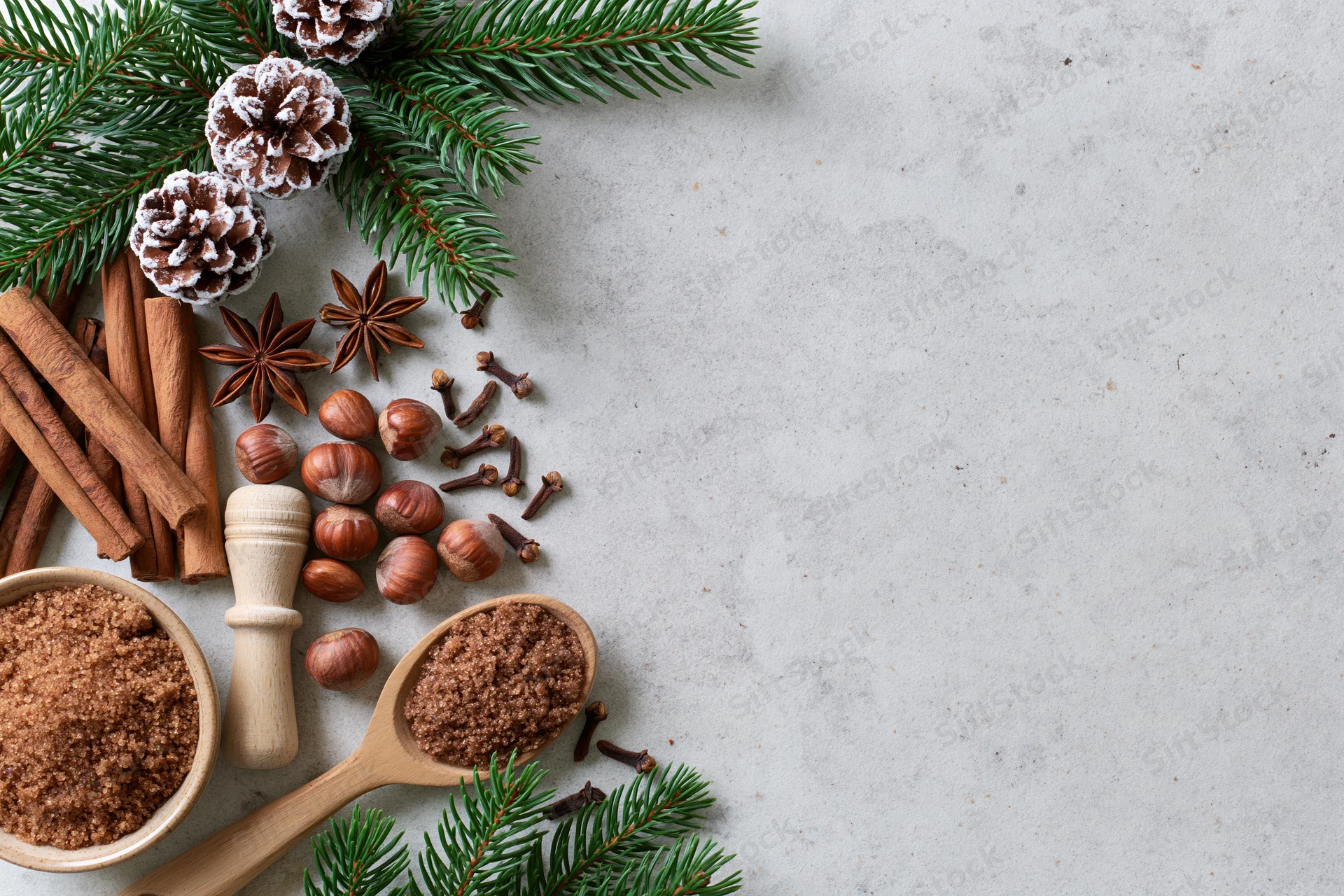 Christmas spices and pine branches arranged on a light surface with copyspace