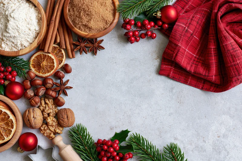 Christmas baking ingredients arranged around a countertop with festive decorations and copyspace