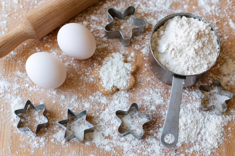 Star-shaped cookie cutters and baking ingredients arranged on a floured wooden countertop
