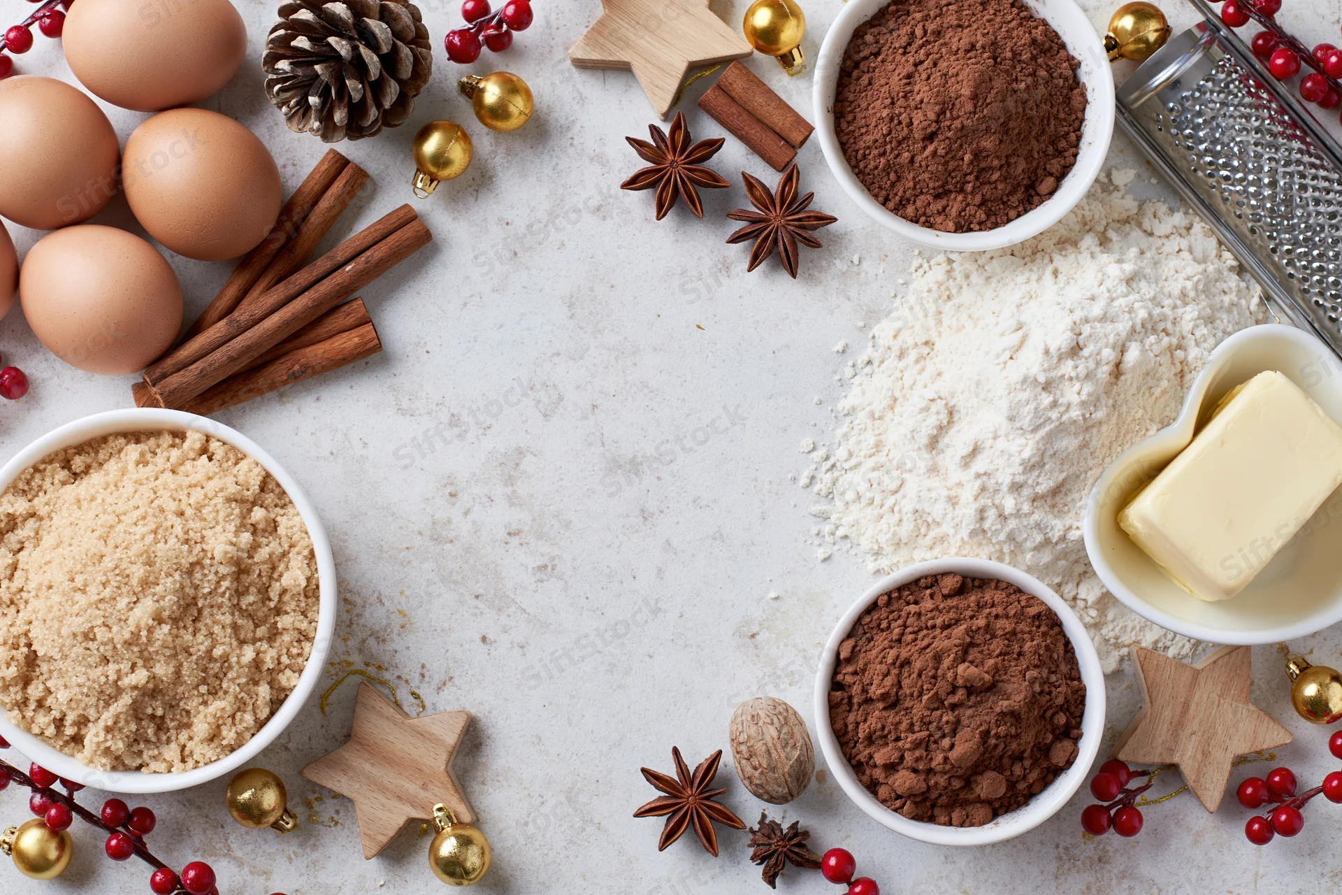 Baking ingredients arranged on a white countertop with christmas decorations and copyspace in center
