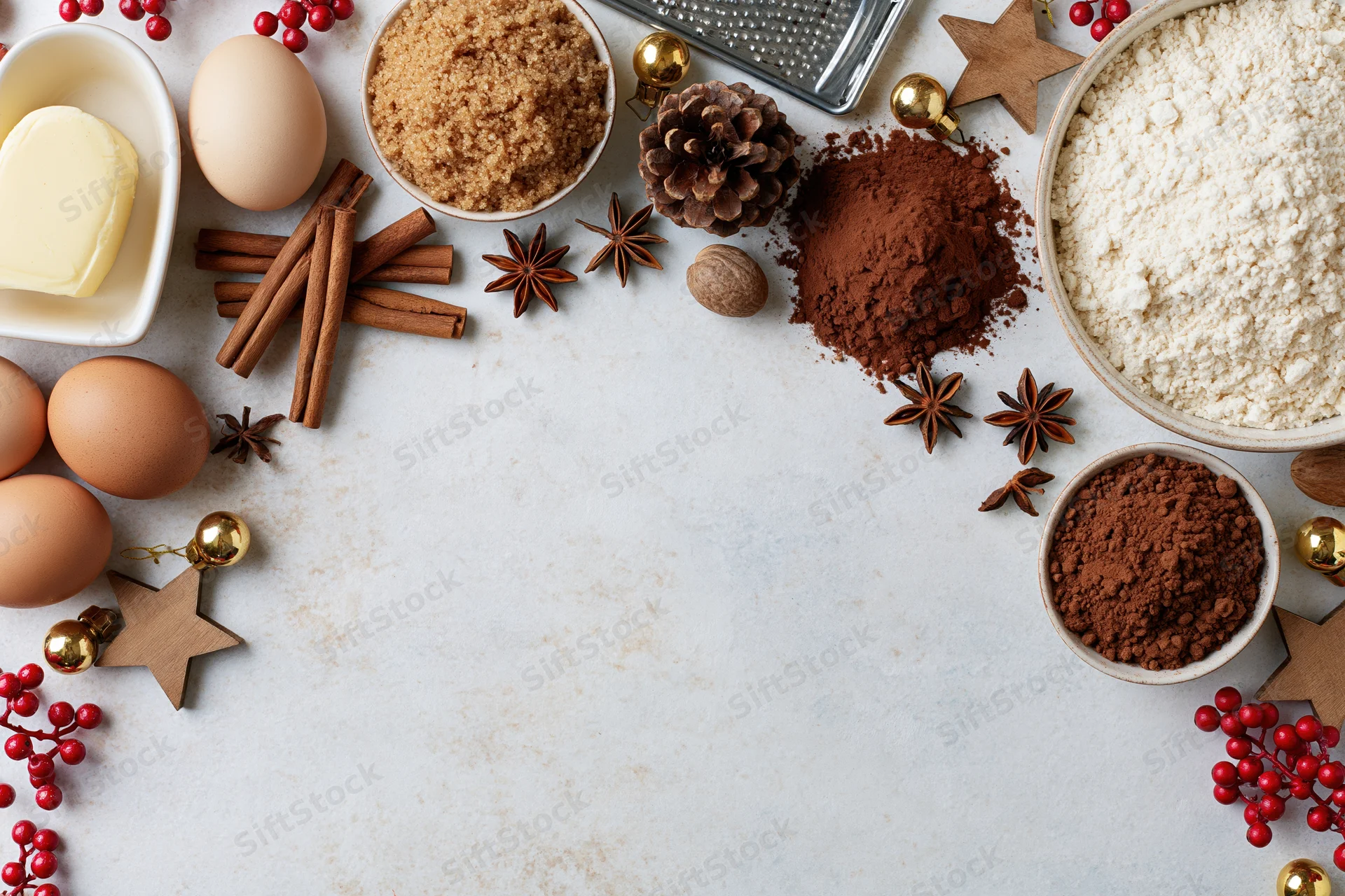 Baking ingredients arranged around a white countertop with holiday decorations and copyspace in center